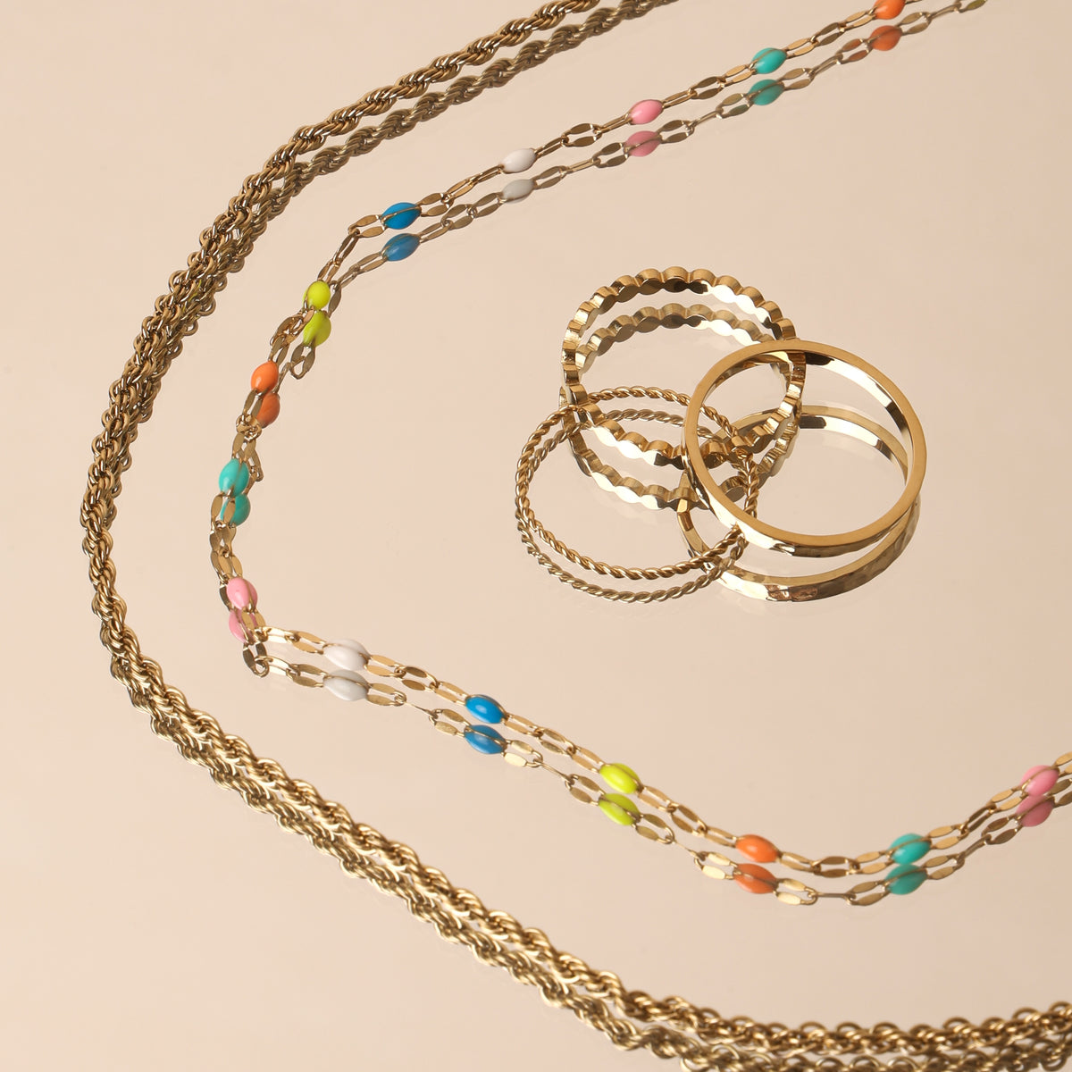 Rainbow dainty choker with a gold rope chain and stacking rings, flat lay
